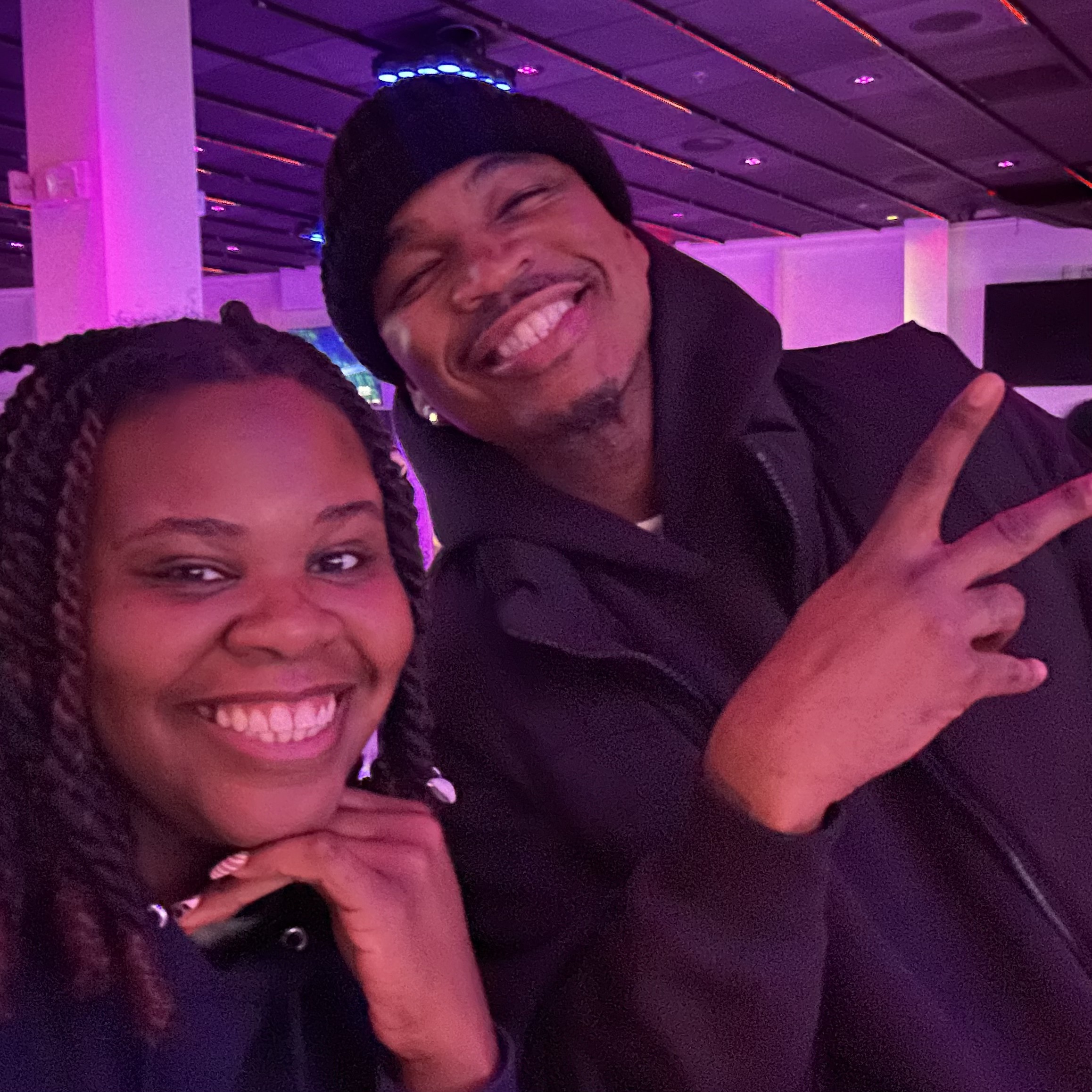 DJ Sam I Am with a performer on a purple-lit venue floor